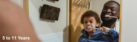 Banner photo of a father and son brushing their teeth looking in to a miror. Wording 